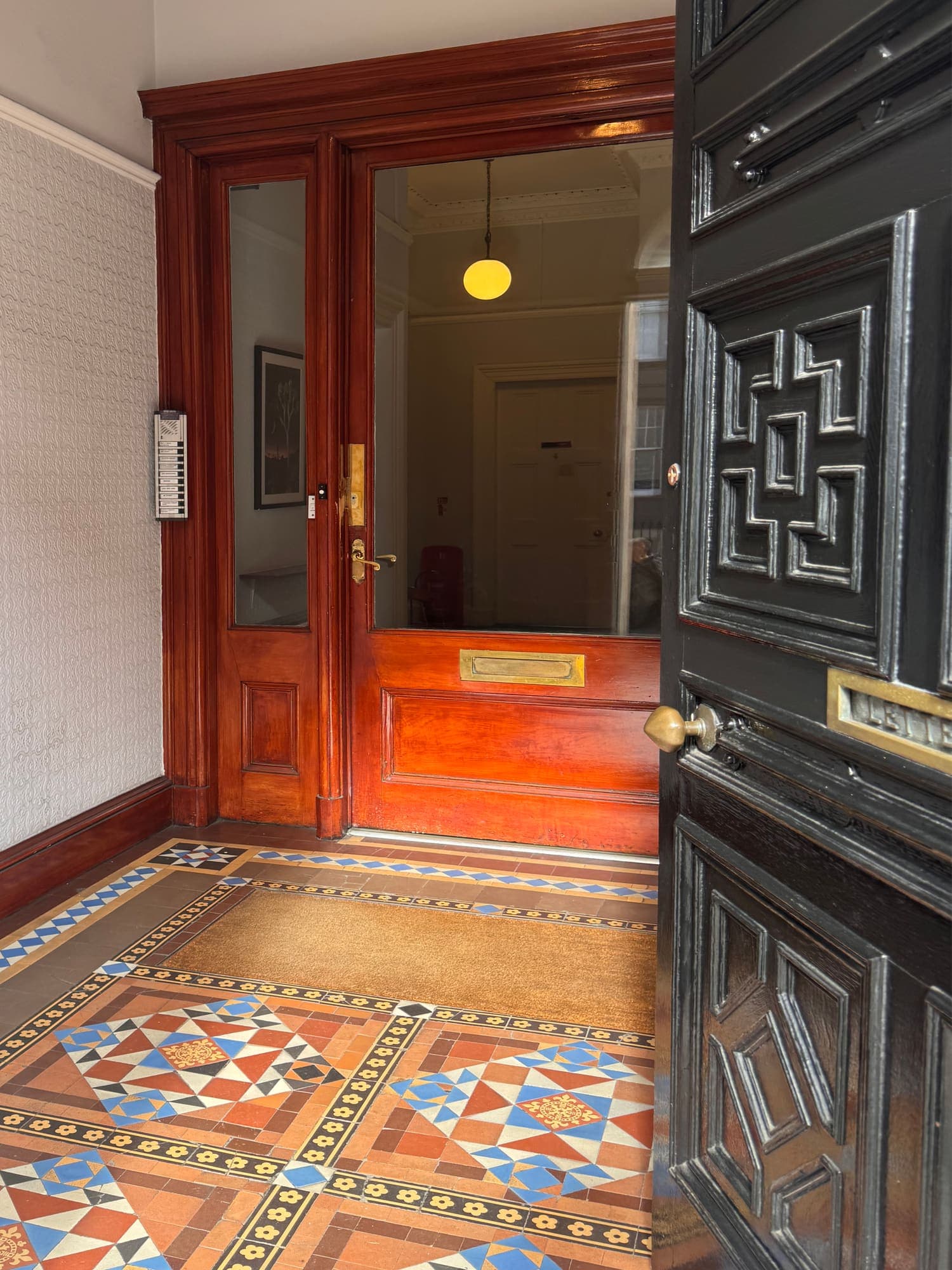 Looking through the open inner door across the entrance hall's Victorian encaustic tiled floor